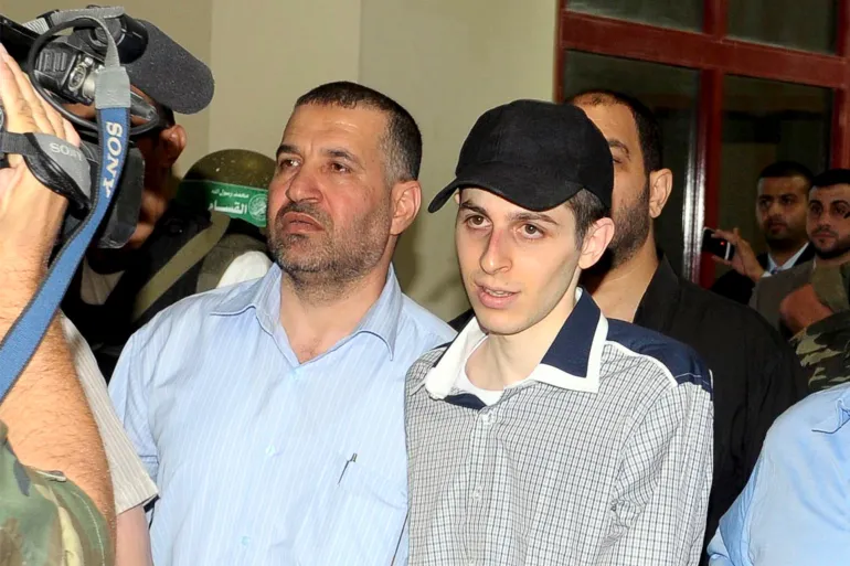 قائد كتائب القسام الشهيد أحمد الجعبري (يسار) قبيل تسليم الجندي جلعاد شاليط (وسط) لإتمام صفقة تبادل الأسرى في 2011 (رويترز)
