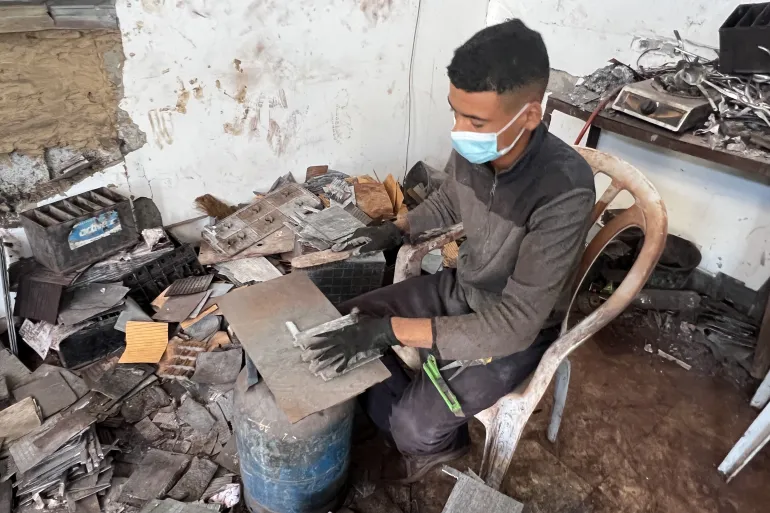 فني ينهمك في فرز وتهيئة الألواح الرصاصية المستعملة تمهيدا لتجميعها وصناعة خلايا طاقة بديلة (الجزيرة)
