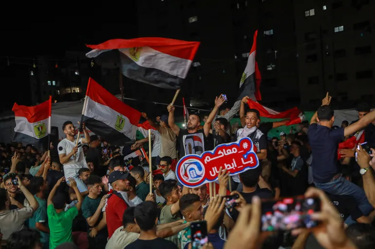 مشجعون فلسطينيون يتجمعون وسط ركام مدينة غزة لمشاهدة مباراة مصر وأستراليا في كأس العالم 2026 عبر شاشة (الأناضول/جيتي).