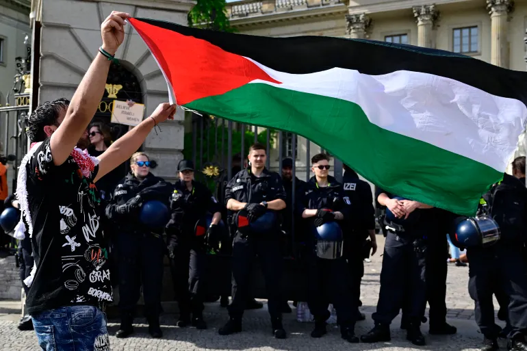 متظاهر يرفع العلم الفلسطيني بينما الشرطة تغلق مدخل جامعة جامعة هومبولت في برلين يوم 3 مايوأيار 2024و وذلك عقب اعتصام مؤيد لغزة (الفرنسية)