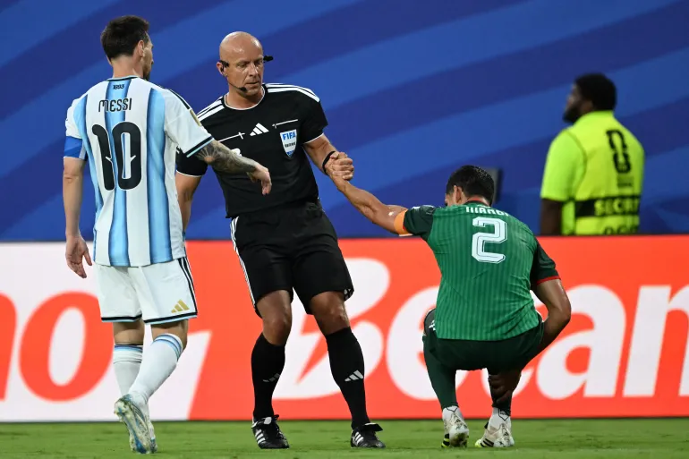 الحكم البولندي شيمون مارتشينياك يساعد مدافع الجزائر عيسى ماندي متغاضيا عن الخطأ الذي قام به الأرجنتيني ليونيل ميسي (الفرنسية)