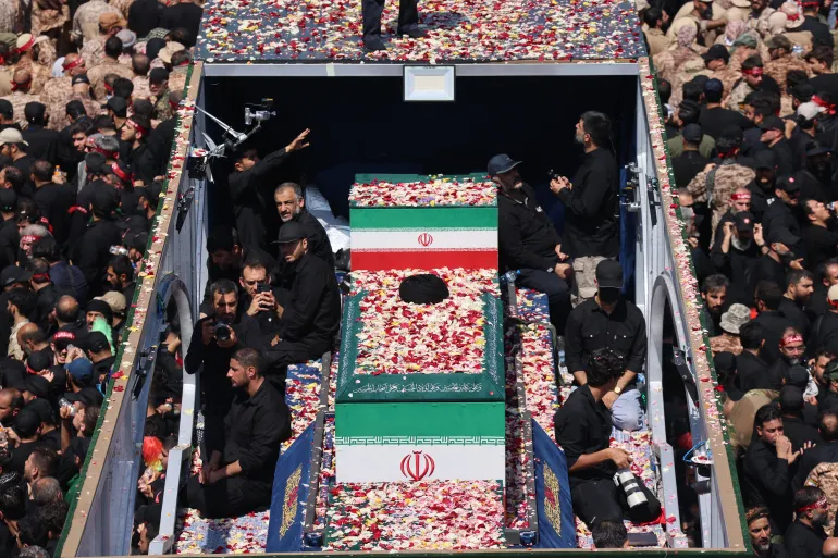 حشود تصطف على جانب أحد الشوارع خلال موكب تشييع المرشد الإيراني الراحل علي خامنئي وعدد من أفراد عائلته في طهران (الفرنسية)