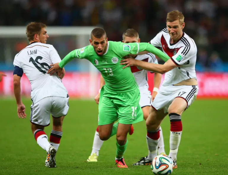 الجزائري إسلام سليماني يمرّ من لاعبي منتخب ألمانيا خلال مباراة دور الـ16 في كأس العالم 2014 بالبرازيل (غيتي)