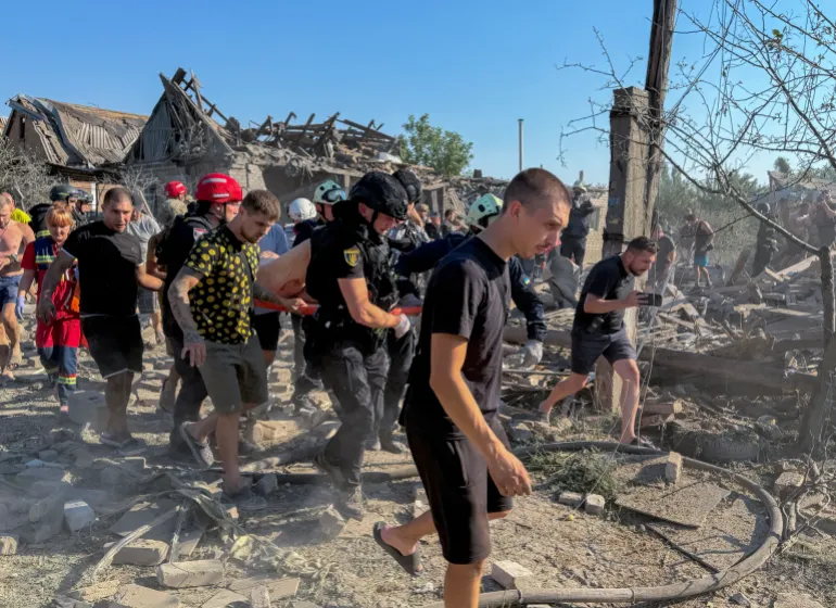 رجال إنقاذ أوكرانيون يحملون ضحية في موقع هجوم روسي على مبانٍ سكنية في زابوروجيا (الأوروبية)