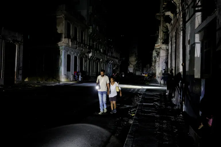 FILE PHOTO: People walk down a street as Cuba's national power grid collapsed, marking the third major outage in nine days, in Havana, Cuba, July 14, 2026. REUTERS/Norlys Perez/File Photo السير في الشوارع المظلمة بات وضعا مألوفا في كوبا (رويترز)