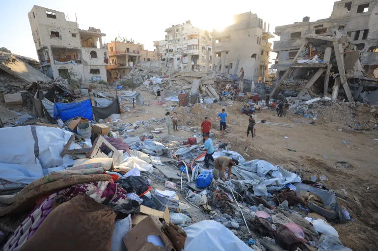 إسراء الرّملي- خاص بالجزيرة نت صورة رقم (7) فلسطين- غربي قطاع غزة- مخيم الشاطئ- 30/07/2026، المربع السكني الذي تم هدمه بالكامل وتضرر المباني حوله بعد استهداف عمارة سكنية لعائلة أبو شمالة بالقرب من دوار القوقا، إسراء الرّملي- خاص بالجزيرة نت. تتضمن خطة إسرائيل بناء مساكن مؤقتة لسكان غزة مع تطبيق إجراءات تدقيق صارمة (الجزيرة)